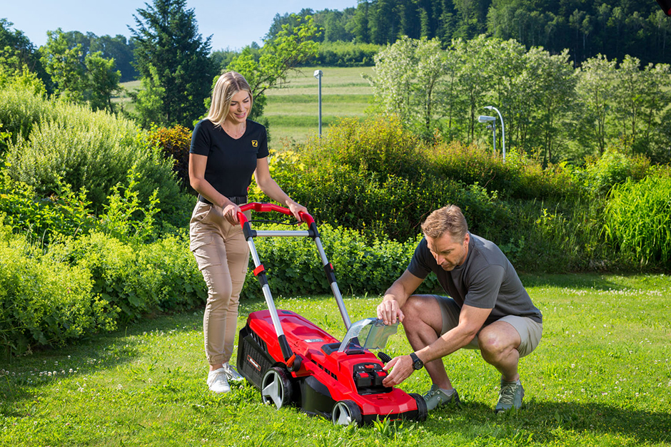 Hans Knauss und junge Frau bei der Gartenarbeit mit einem Akku-Rasenmäher von EINHELL | Credit: ZGONC