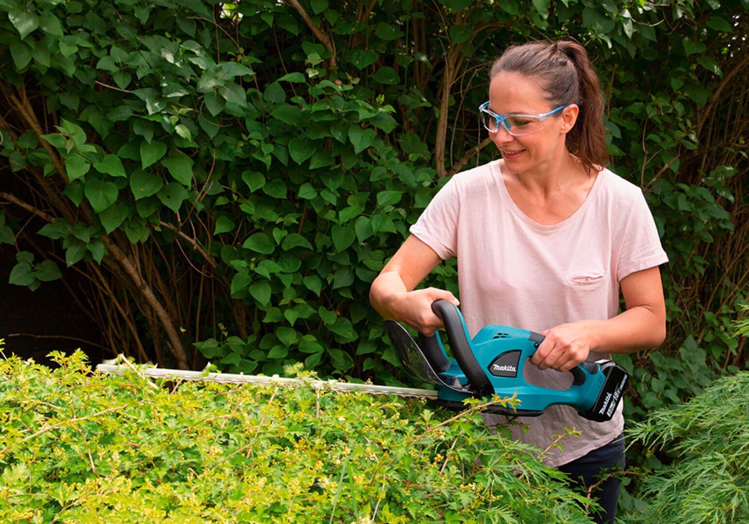Junge Frau bei der Gartenarbeit mit einer Heckenschere von MAKITA | Credit: ZGONC