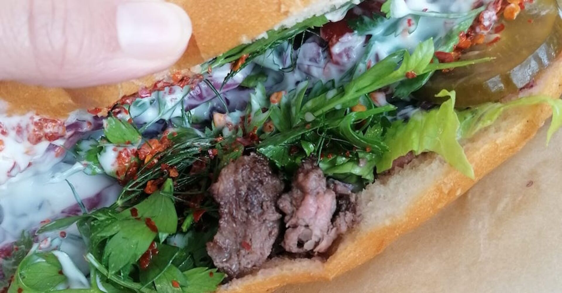 Großaufnahme des Döner-Sandwiches aus der Gumpendorferstraße: Fleisch, Koriander, Zwiebel, Sauce, Gurke, Chili und Rotkraut