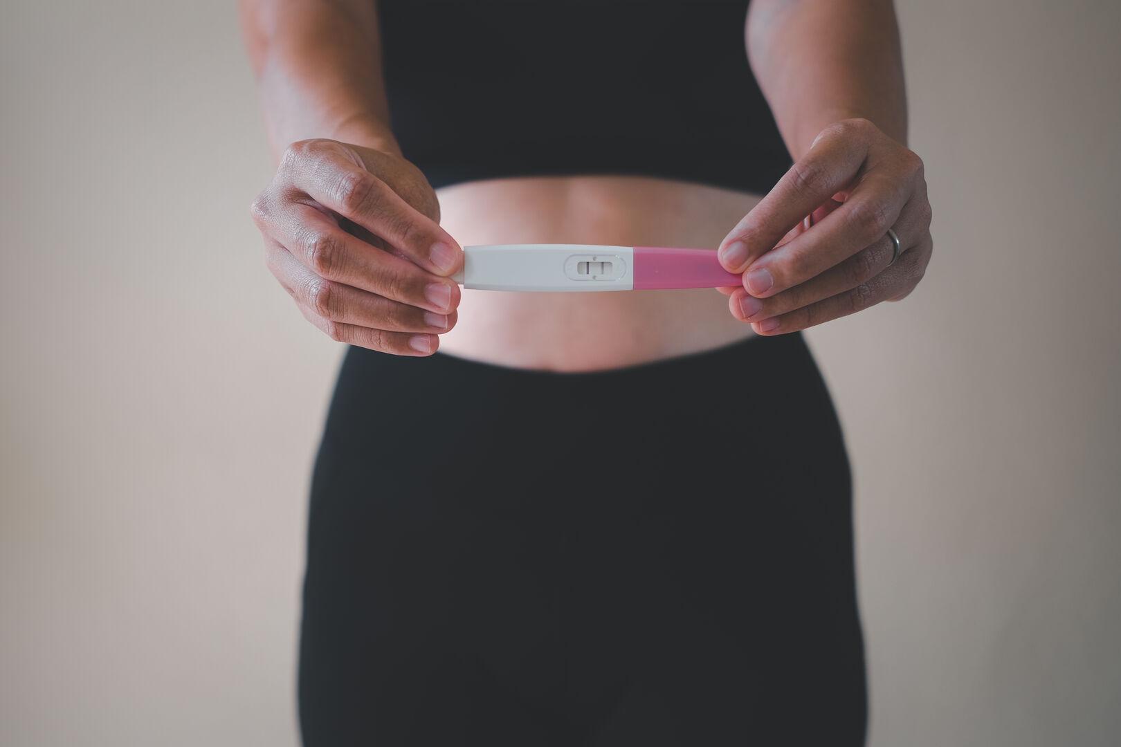 Frau hält positiven Schwangerschaftstest in den Händen