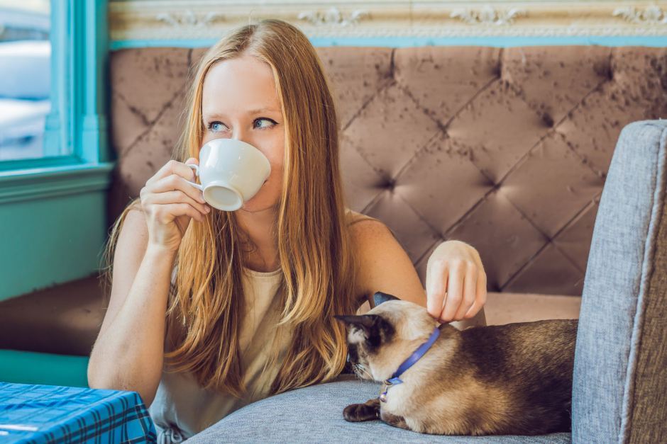 Junge Frau bei einer Tasse Kaffee in Gesellschaft einer Katze | Credit: iStock.com/galitskaya