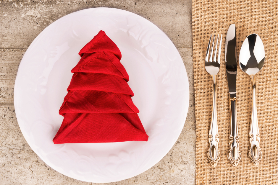 Tannenbaum nach Origami-Falttechnik als Tischdekoration auf einem Essteller | Credit: iStock.com/MikeyGen73