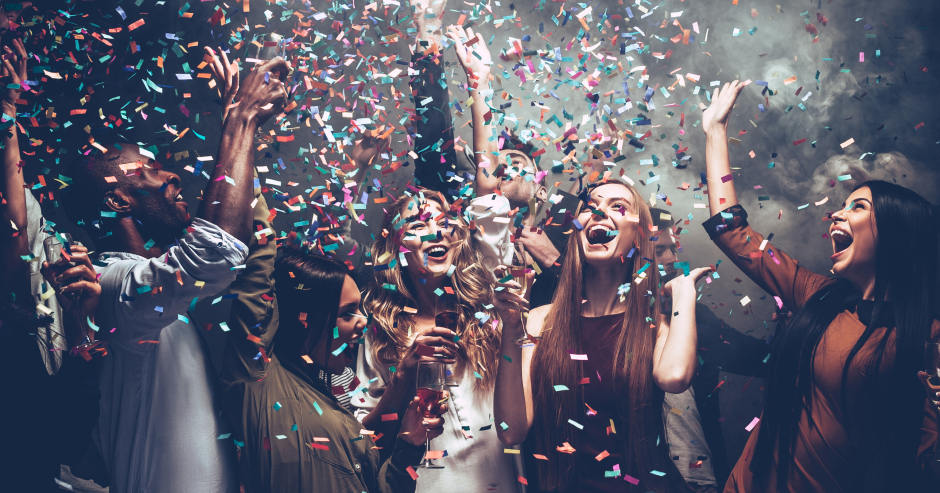 Junge Gruppe an Menschen feiert ausgelassen im Konfetti-Regen | Credit: iStock.com/g-stockstudio