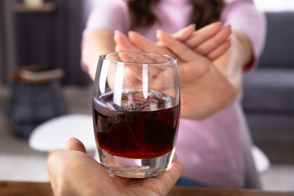 Frau weist ein Glas Rotwein, das ihr angeboten wird, energisch zurück | Credit: iStock.com/AndreyPopov