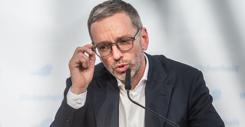 Herbert Kickl bei einer Pressekonferenz der FPÖ. Er spricht in ein Mikrofon und rückt seine Brille zurecht.
