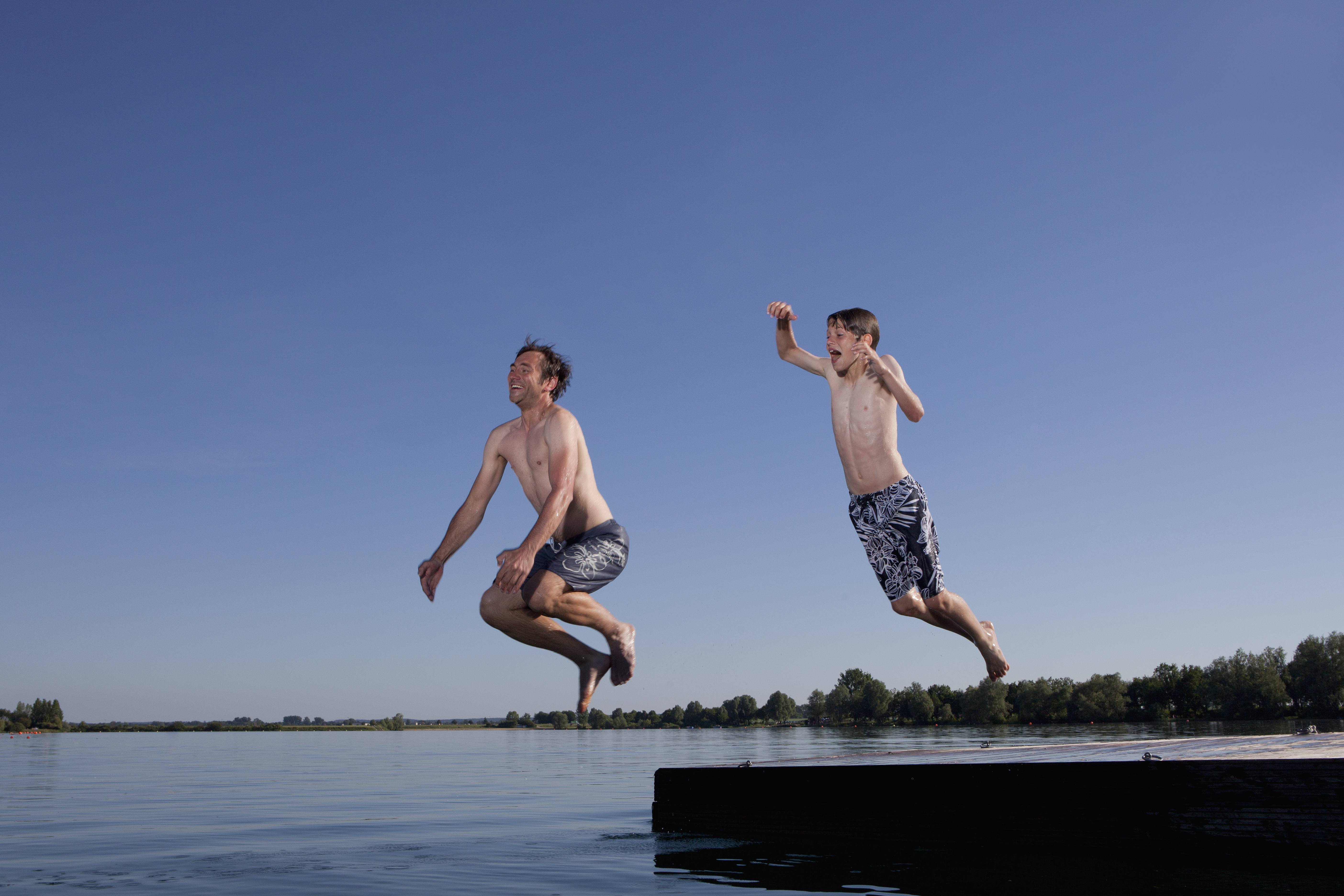 Vater und Sohn springen in einen See | Credit: iStock.com/Johnny Valley