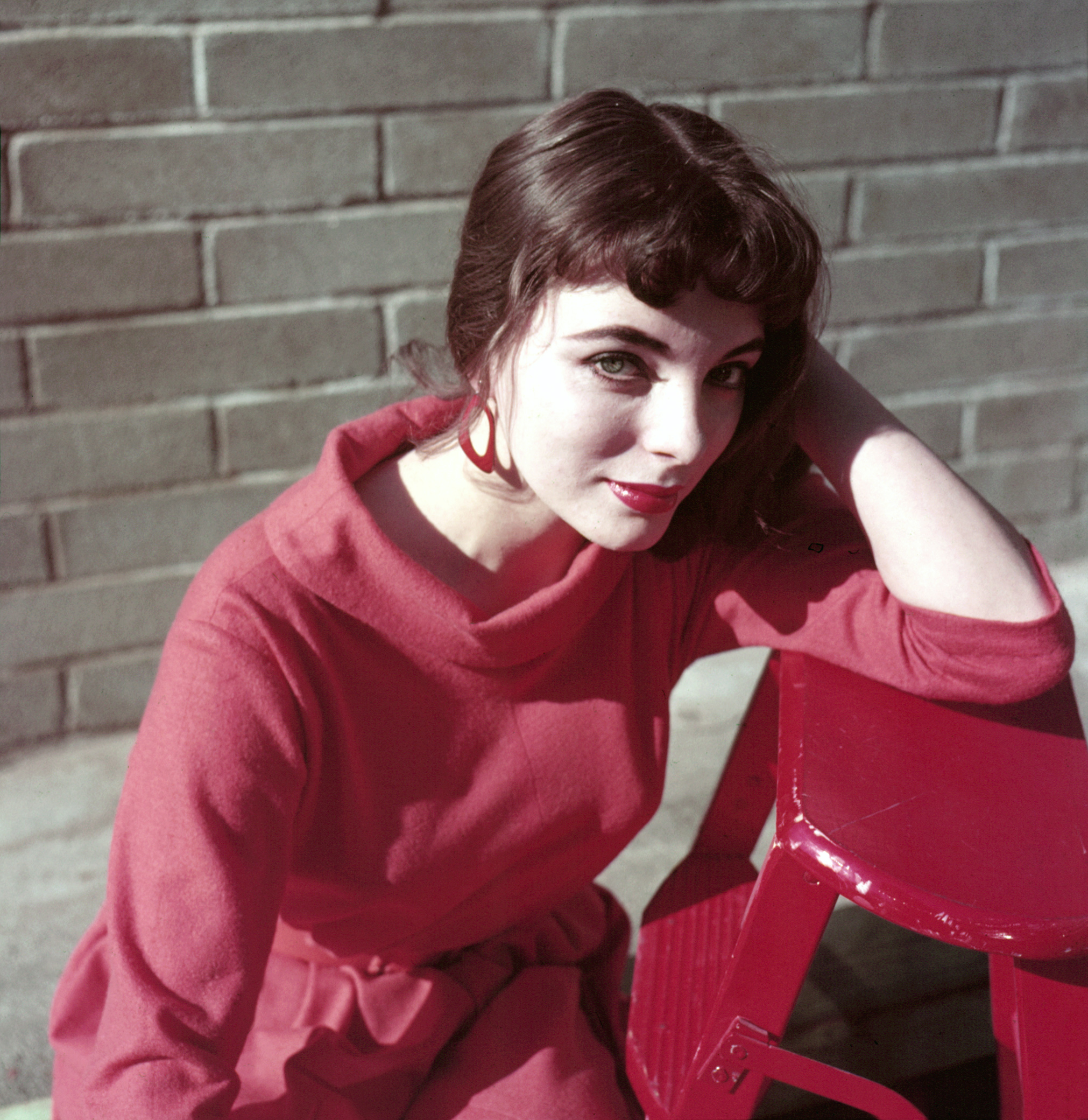 Modeaufnahme von Joan Collins in einem roten Kostüm.