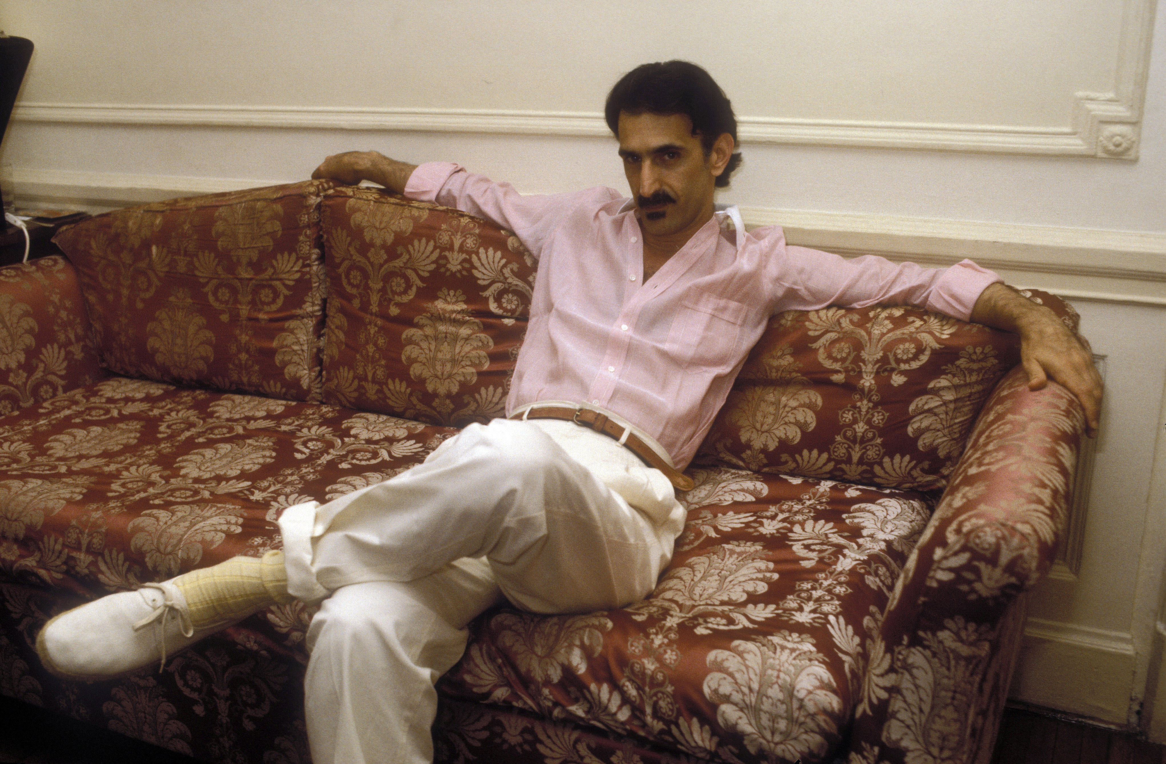 Frank Zappa der lässig auf einem Sofa sitzt.