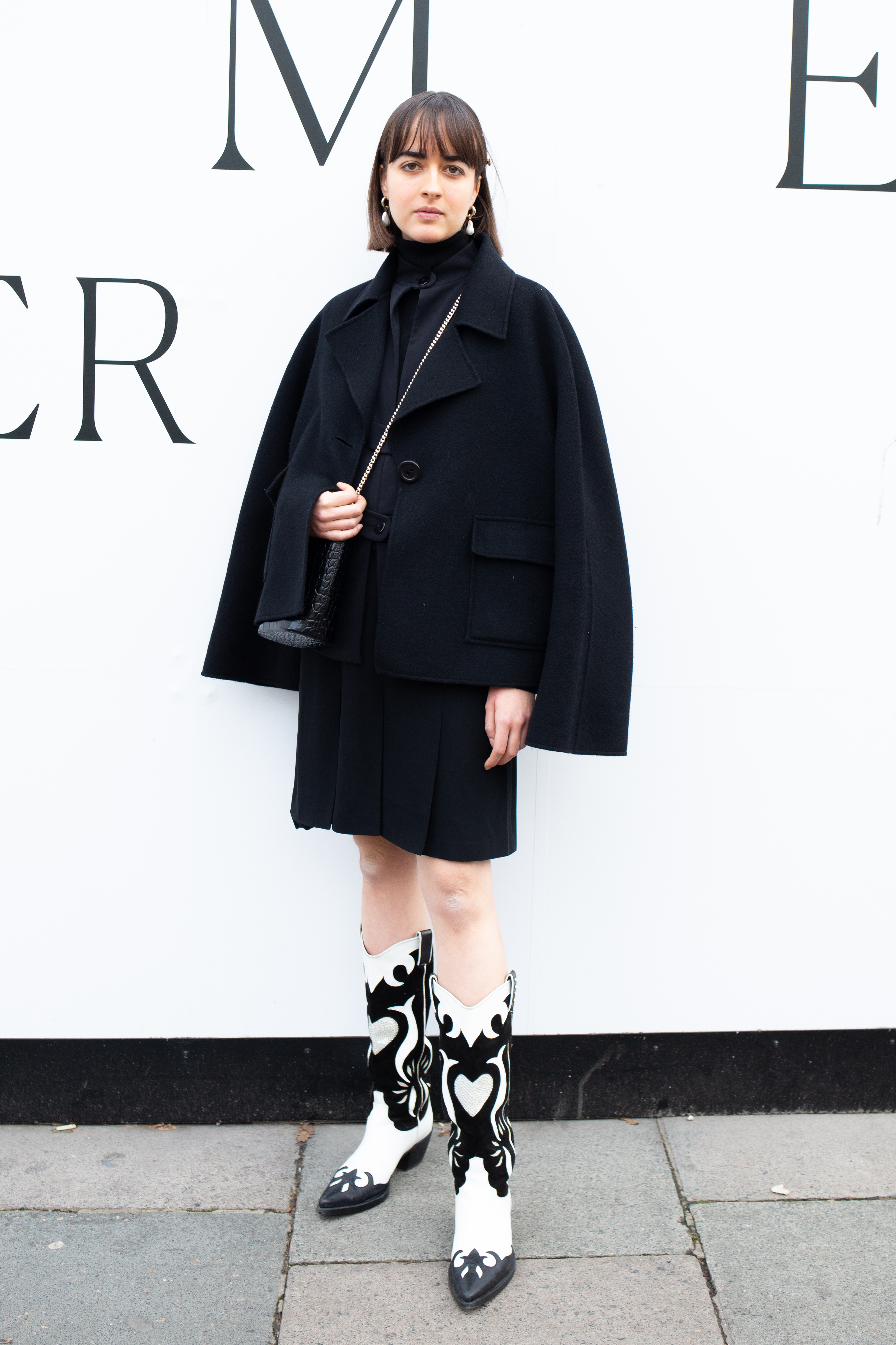 Eine Frau trägt ein schwarzes Outfit und schwarz-weiße Boots