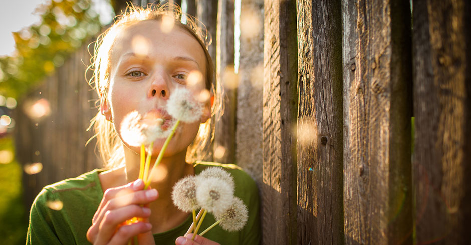 Junge Frau mit einem Strauß Löwenzahn in der Hand | Credit: iStock.com/ViktorCap