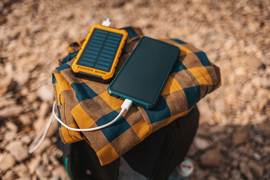 Smartphone wird über eine solarbetriebene Powerbank aufgeladen | Credit: iStock.com/Ildar Abulkhanov