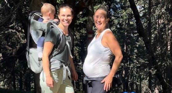 Anna Veith trägt ihren Sohn Henry in einer Trage auf dem Rücken, Michaela Kirchgasser ist mit Babybauch zu sehen