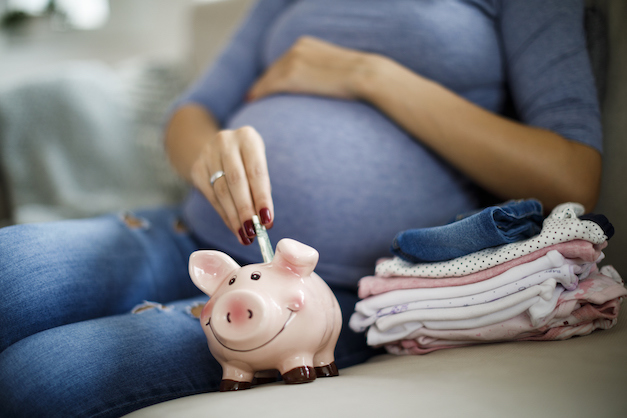 Schwangere wirft Geld ins Sparschwein