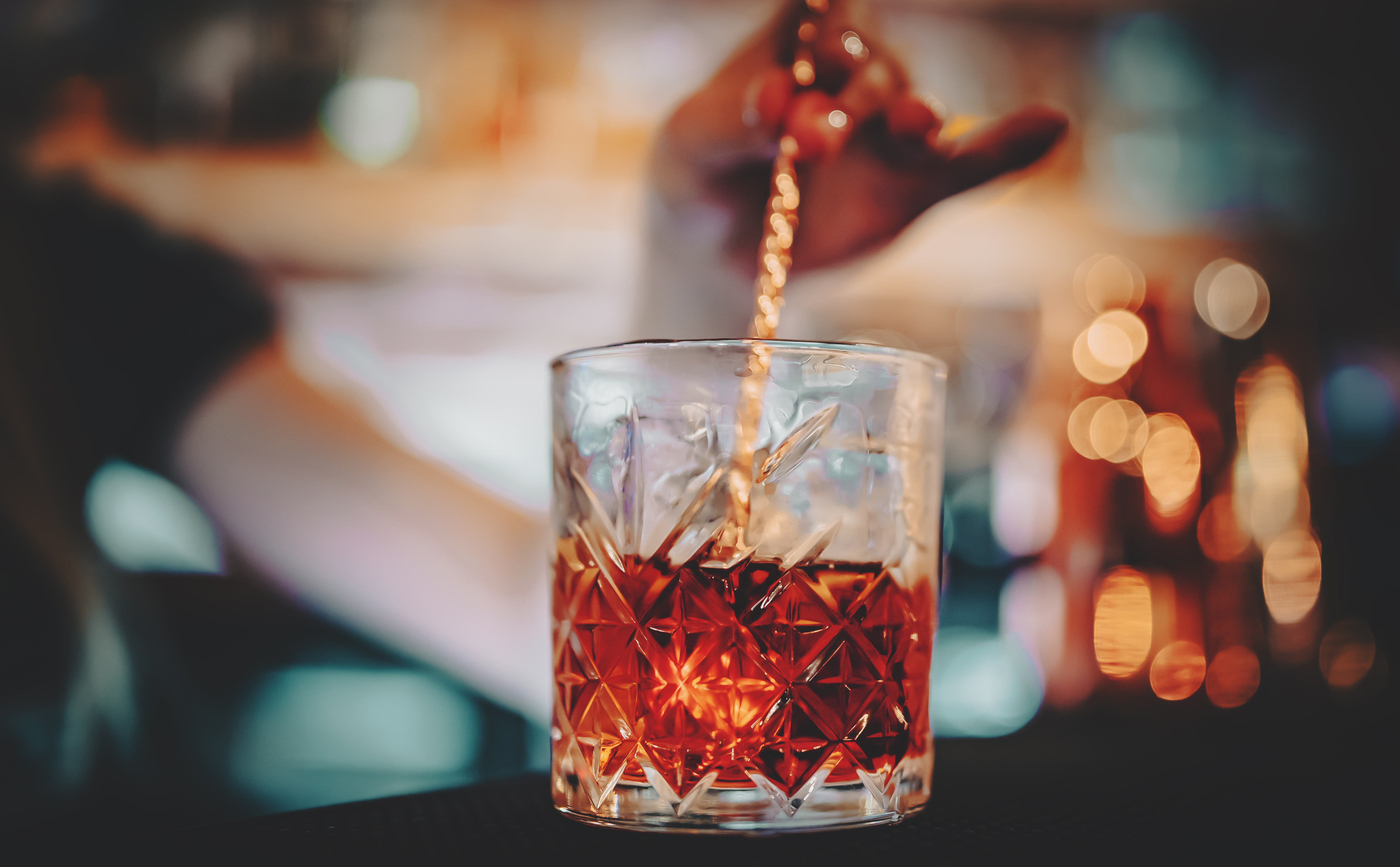 Glas mit Rührstäbchen und rotem Cocktail Negroni