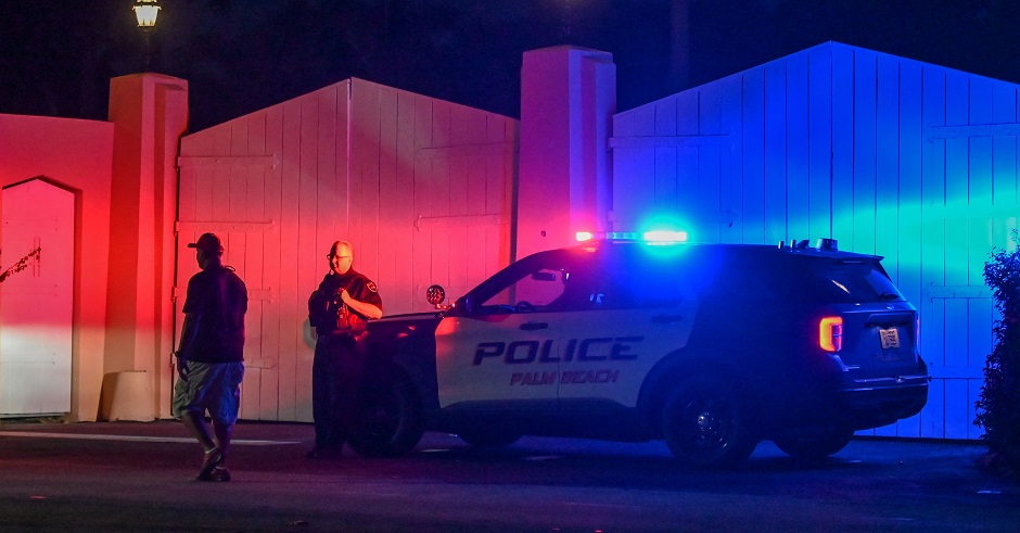 Ein Polizeiauto steht mit Blaulicht vor den Toren von Trumps Anwesen.