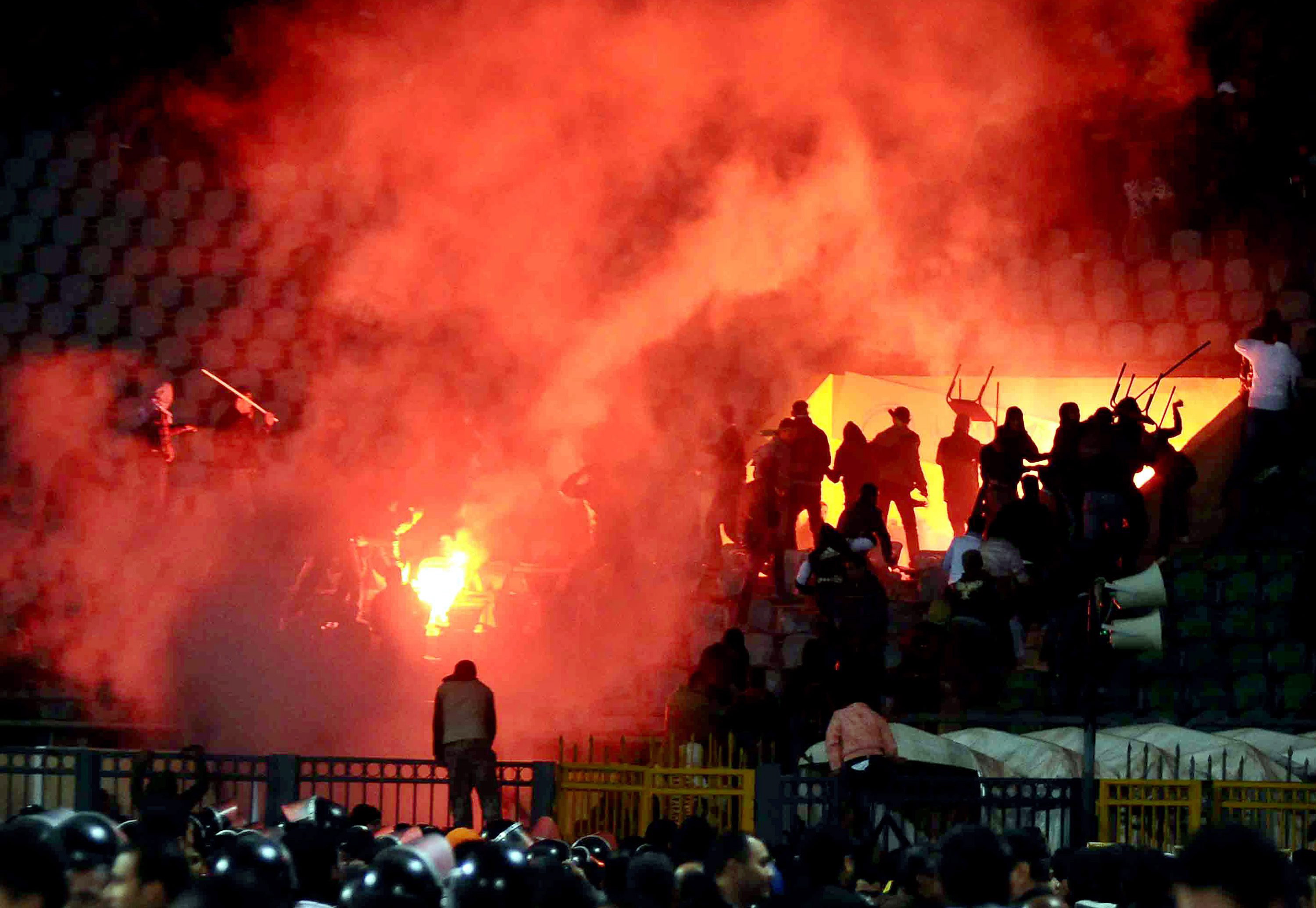 Ausschreitungen vor einer brennenden Tribüne in einem Fußballstadion