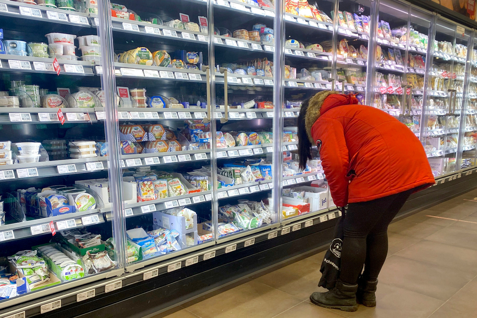 Frau bückt sich und schaut auf untere Supermarktregale. | Credit: Frank Hoermann / dpa Picture Alliance / picturedesk.com