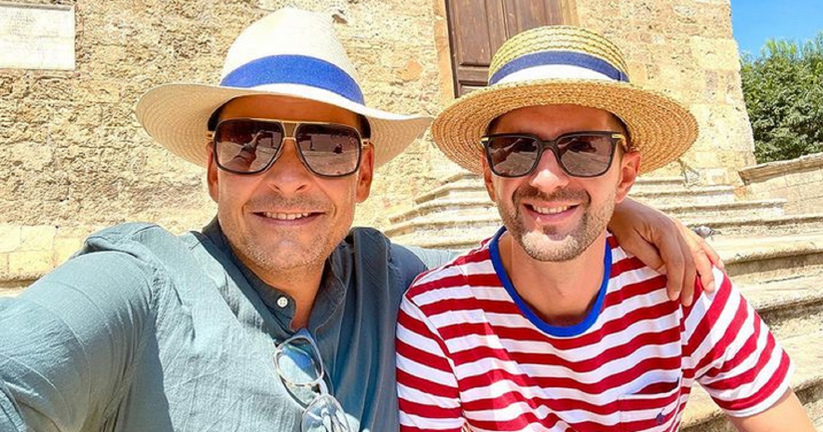 Ein Selfie von Gerald Grosz und seinem Ehemann. Beide tragen Sonnenhüte und Sonnebrillen