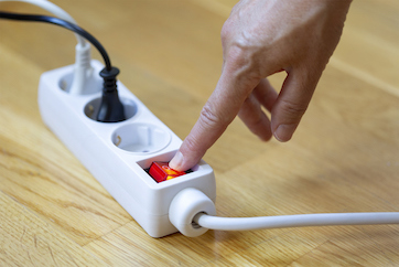 Rote Taste einer weißen Steckdosenleiste wird gedrückt