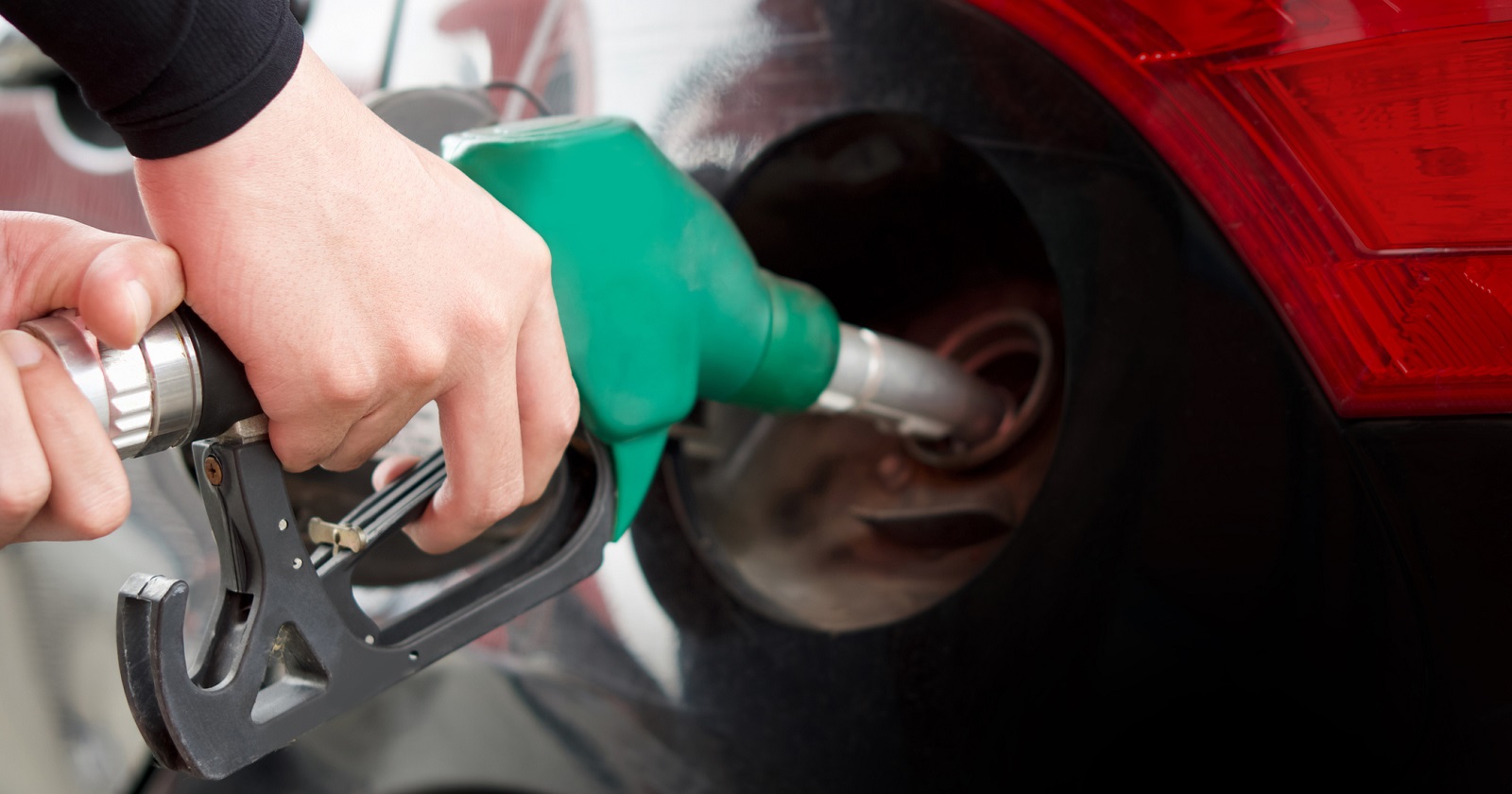 Nahaufnahme beim Tanken. Eine Frauenhand hält einen Tankhahn in der Hand und tank ihr Auto.