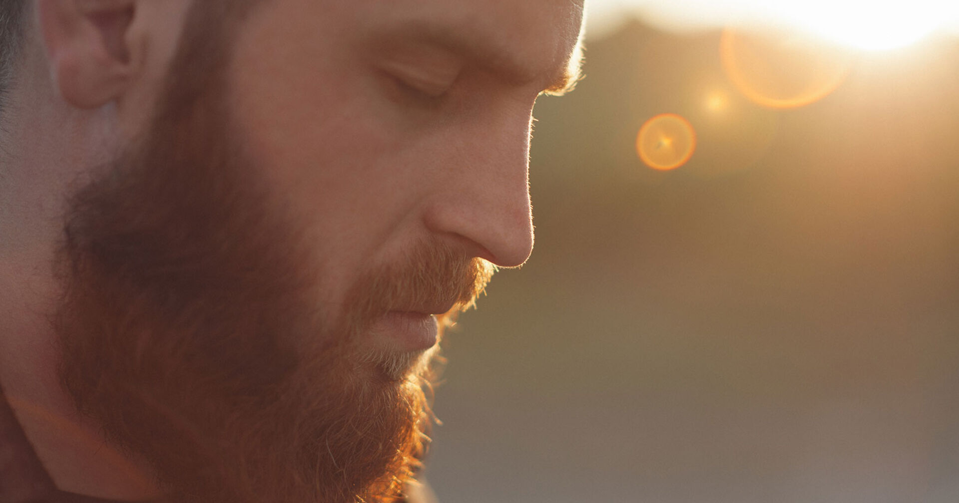 Junger Mann mit Vollbart beim Meditieren bei geschlossenen Augen | Credit: iStock.com/Ruslanshug