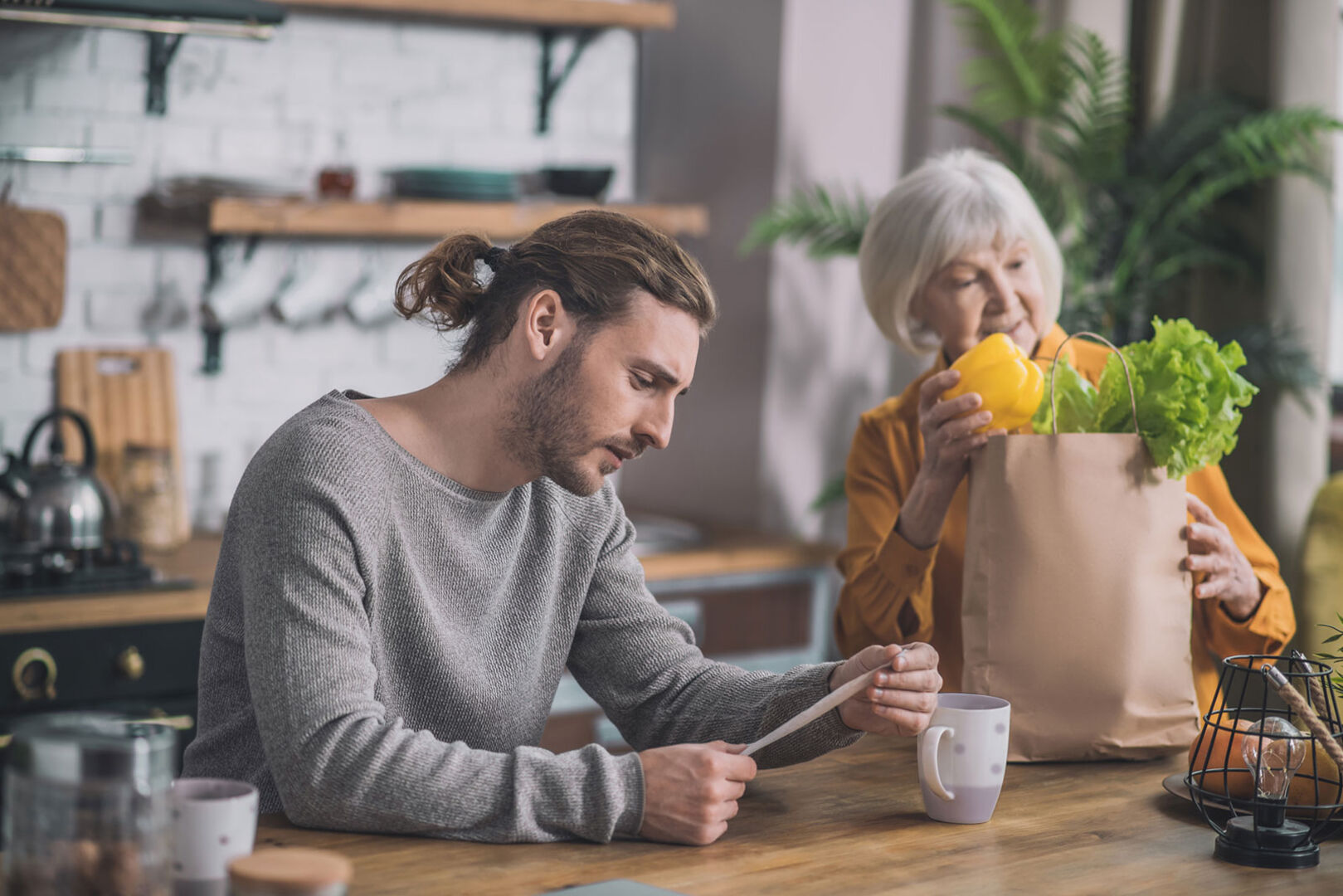 Junger Mann mit der Einkaufsliste in der Hand in der Küche | Credit: iStock.com/Zinkevych
