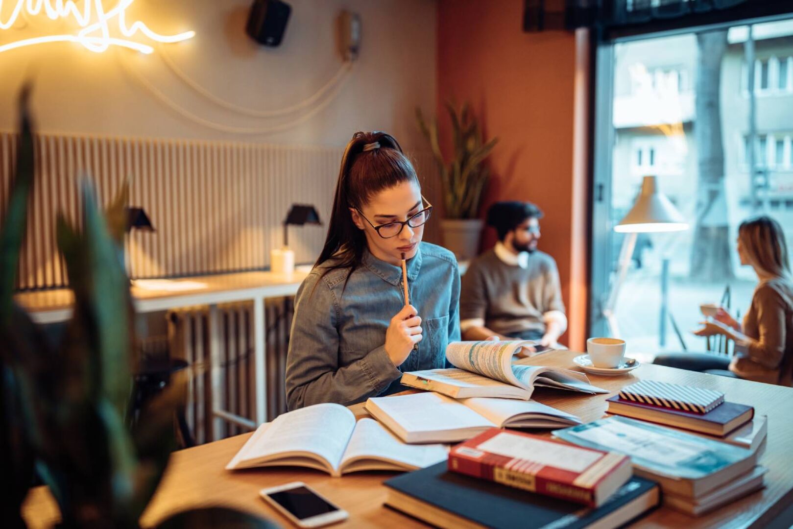 Junge Studentin beim Lernen im Café | Credit: iStock.com/bernardbodo
