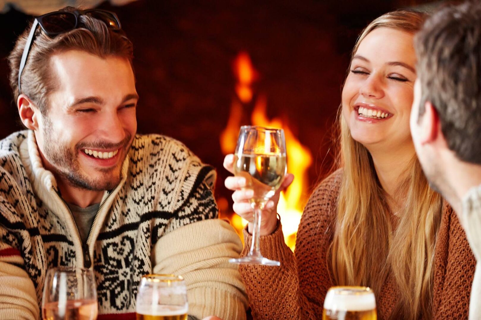 Gesellige Runde junger Frauen und Männer vor dem Kamin | Credit: iStock.com/Chris Cross