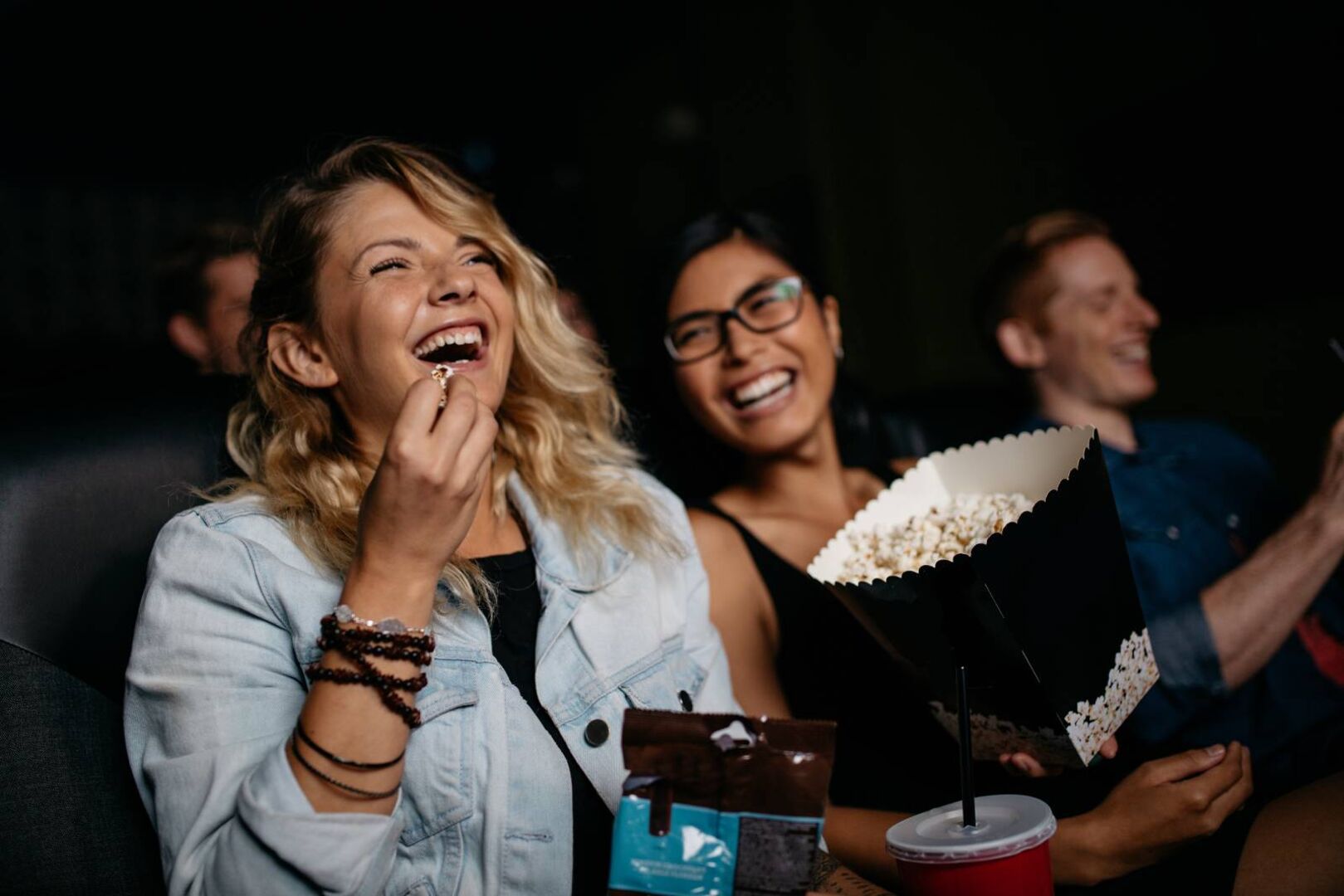 Junge Frauen beim gemeinsamen Kinobesuch mit Popcorn | Credit: iStock.com/Jacob Ammentorp Lund