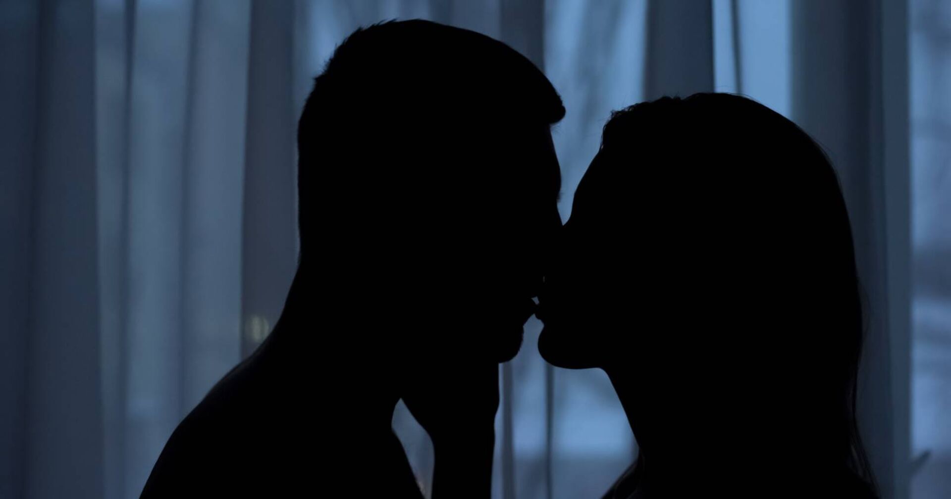 Eine Frau und ein Mann küssen sich in der Dunkelheit | Credit: iStock.com/Motortion