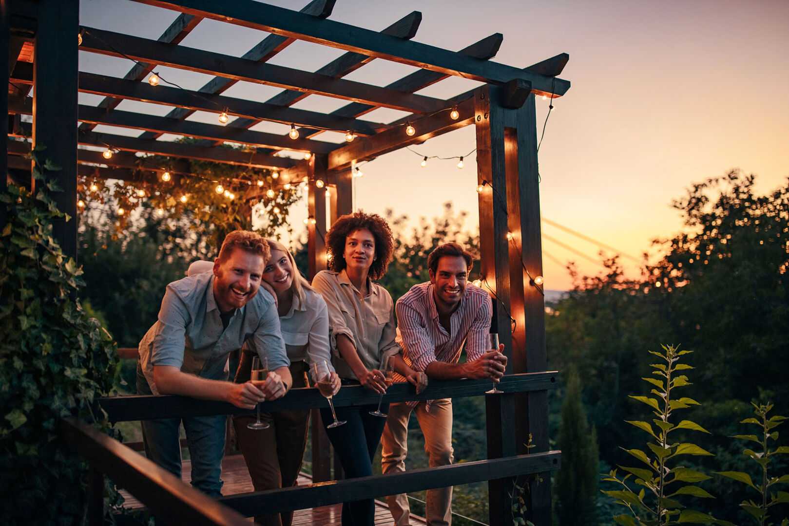 Zwei Paare genießen den Sommerabend auf ihrer begrünten Terrasse | Credit: iStock.com/bernardbodo