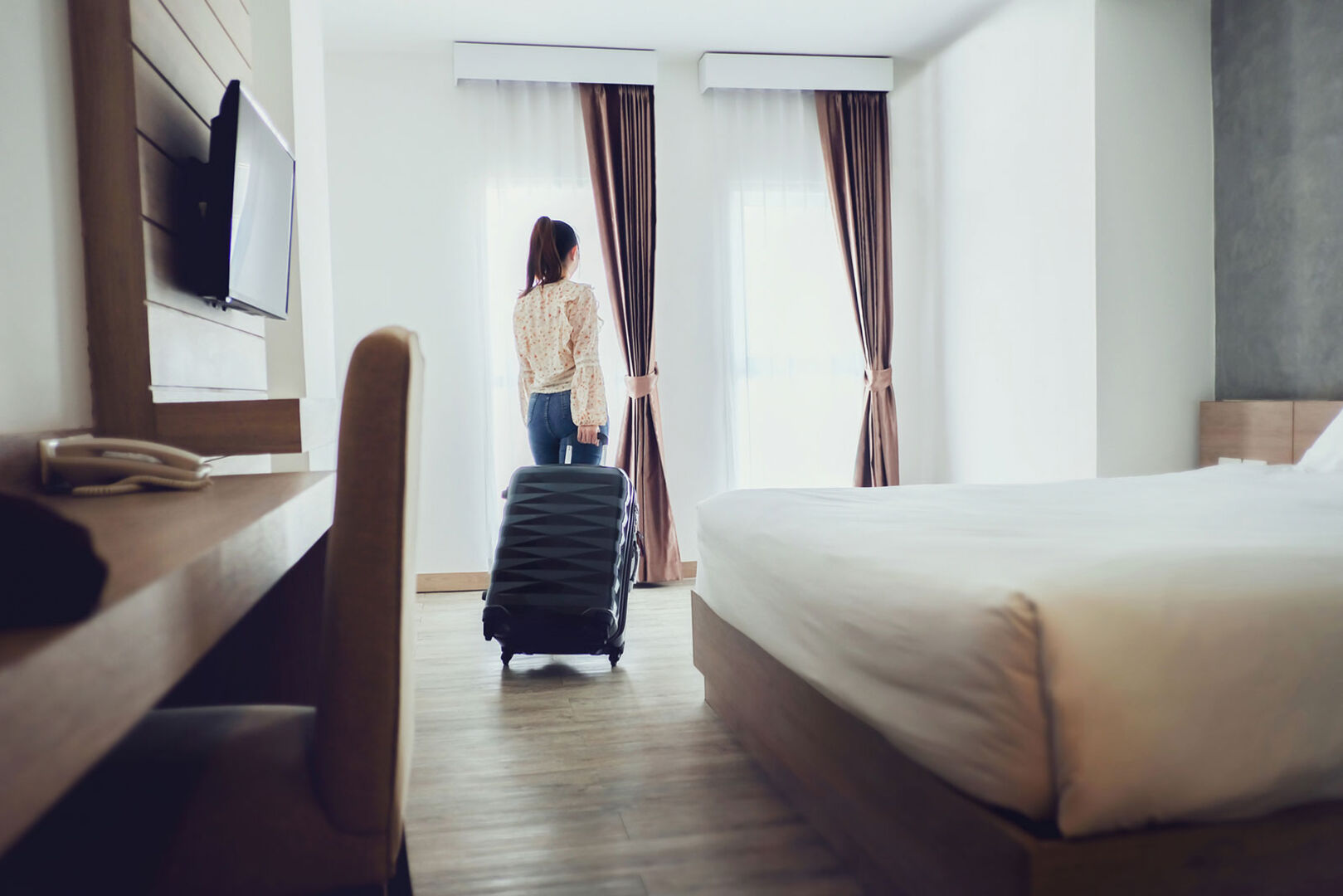 Junge Frau quartiert sich in ihrem Hotelzimmer ein | Credit: iStock.com/oatawa