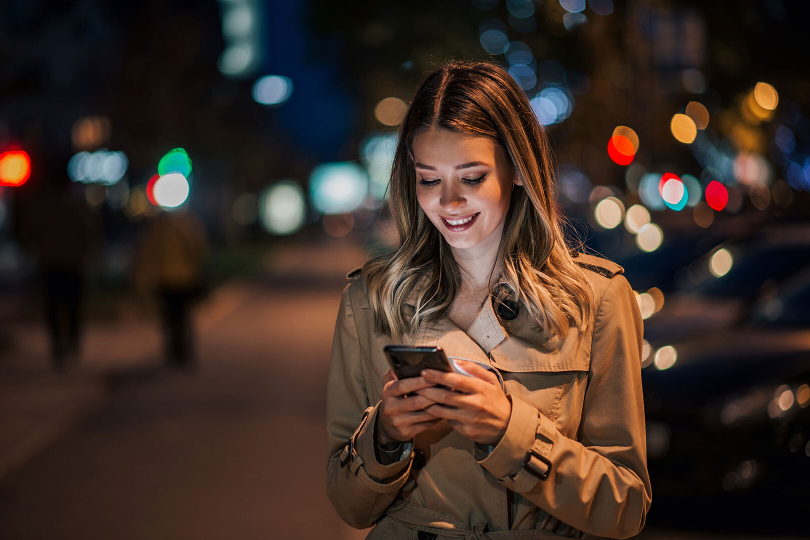 Junge Frau abends unterwegs in der Stadt mit ihrem Smartphone | Credit: iStock.com/nortonrsx