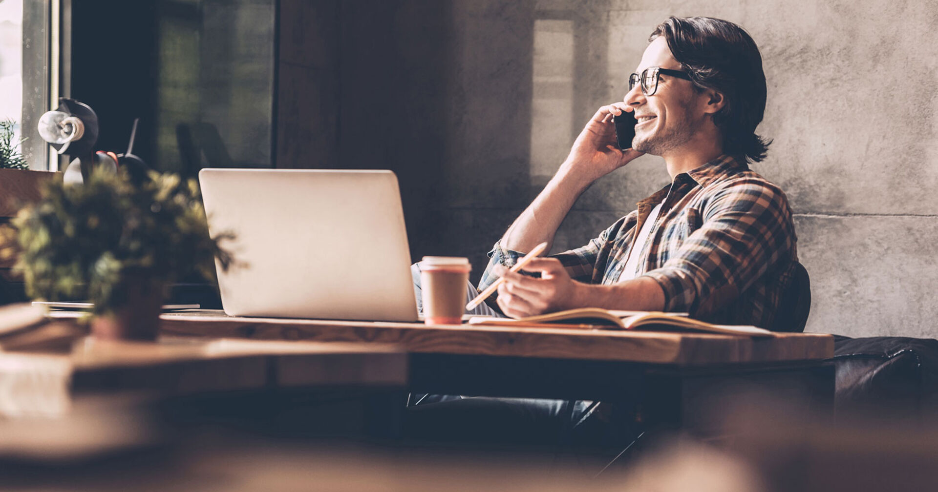 Junger Mann mit Brille telefoniert in seinem Büro | Credit: iStock.com/g-stockstudio