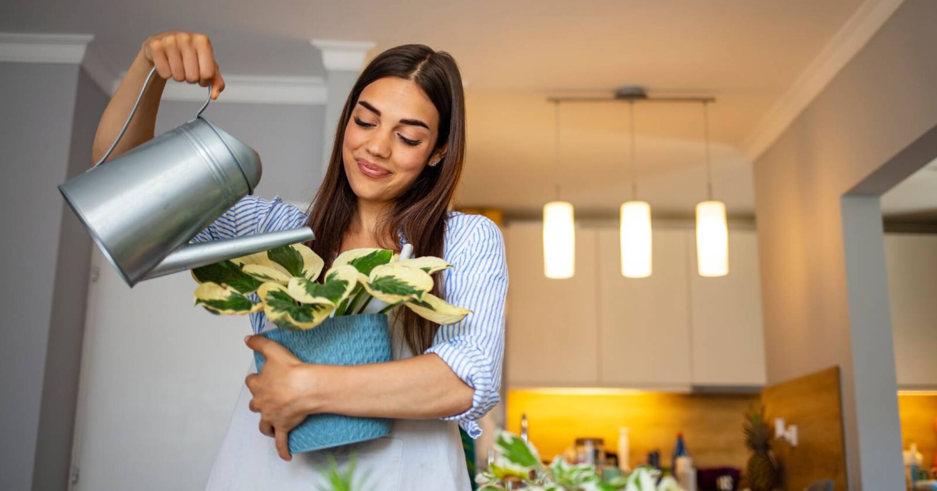 Junge Frau gießt ihre Zimmerpflanze | Credit: iStock.com/dragana991