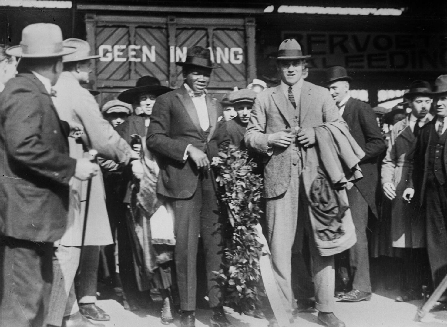 Der in einen eleganten Anzug gekleidete Boxer Battling Siki, der auf einem Bahnsteig feierlich empfangen wird.