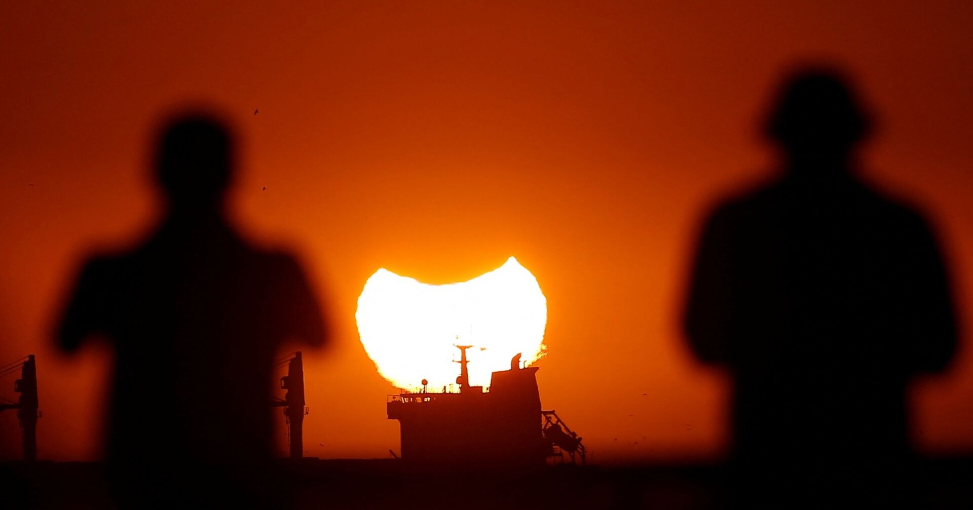 Zwei Personen beobachten eine partielle Sonnenfinsternis. | Credit: RODRIGO GARRIDO / REUTERS / picturedesk.com