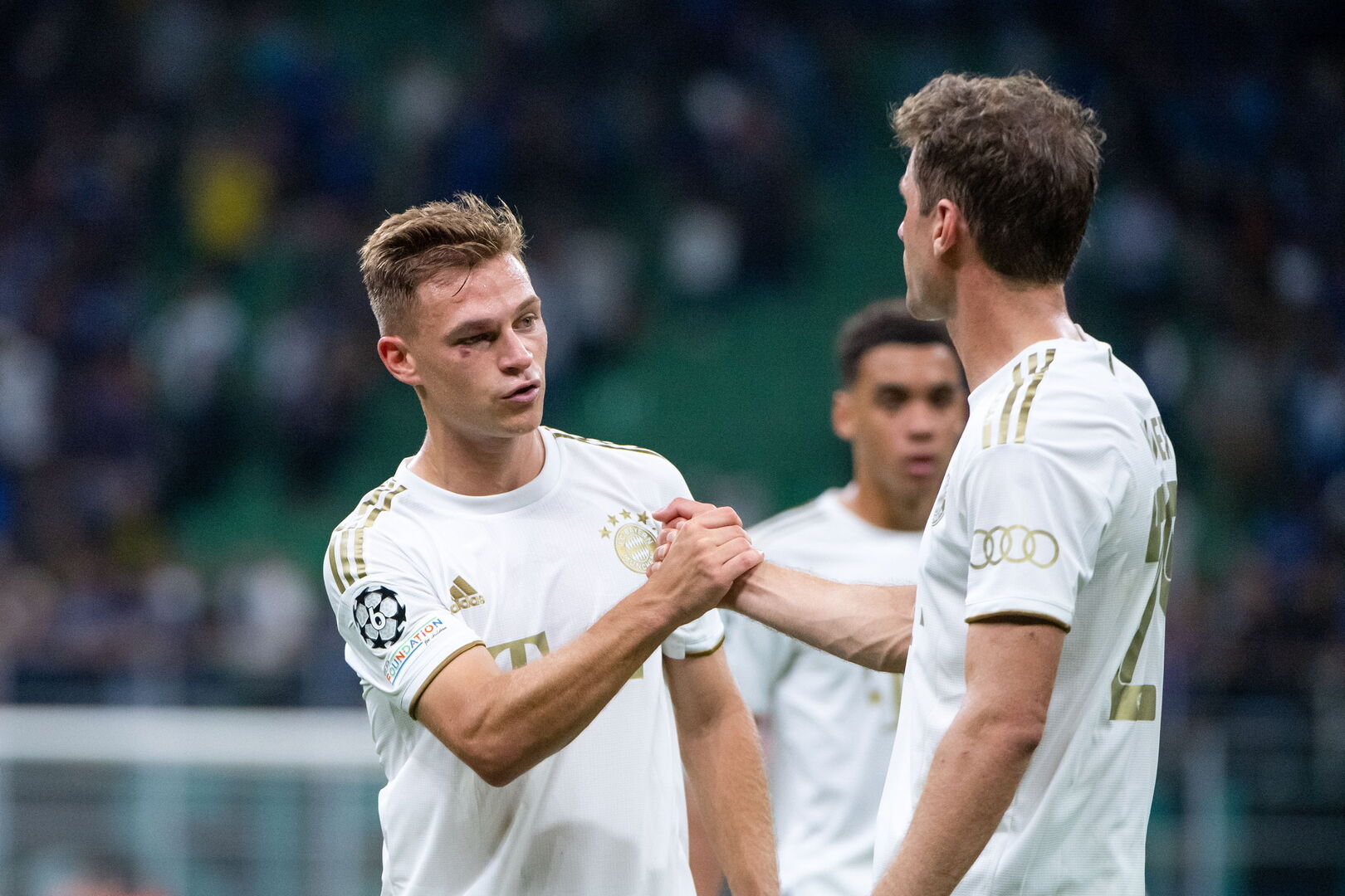 Die deutschen Nationalspieler Thomas Müller und Joshua Kimmich, die auf dem Fußballfeld einen Handschlag durchführen