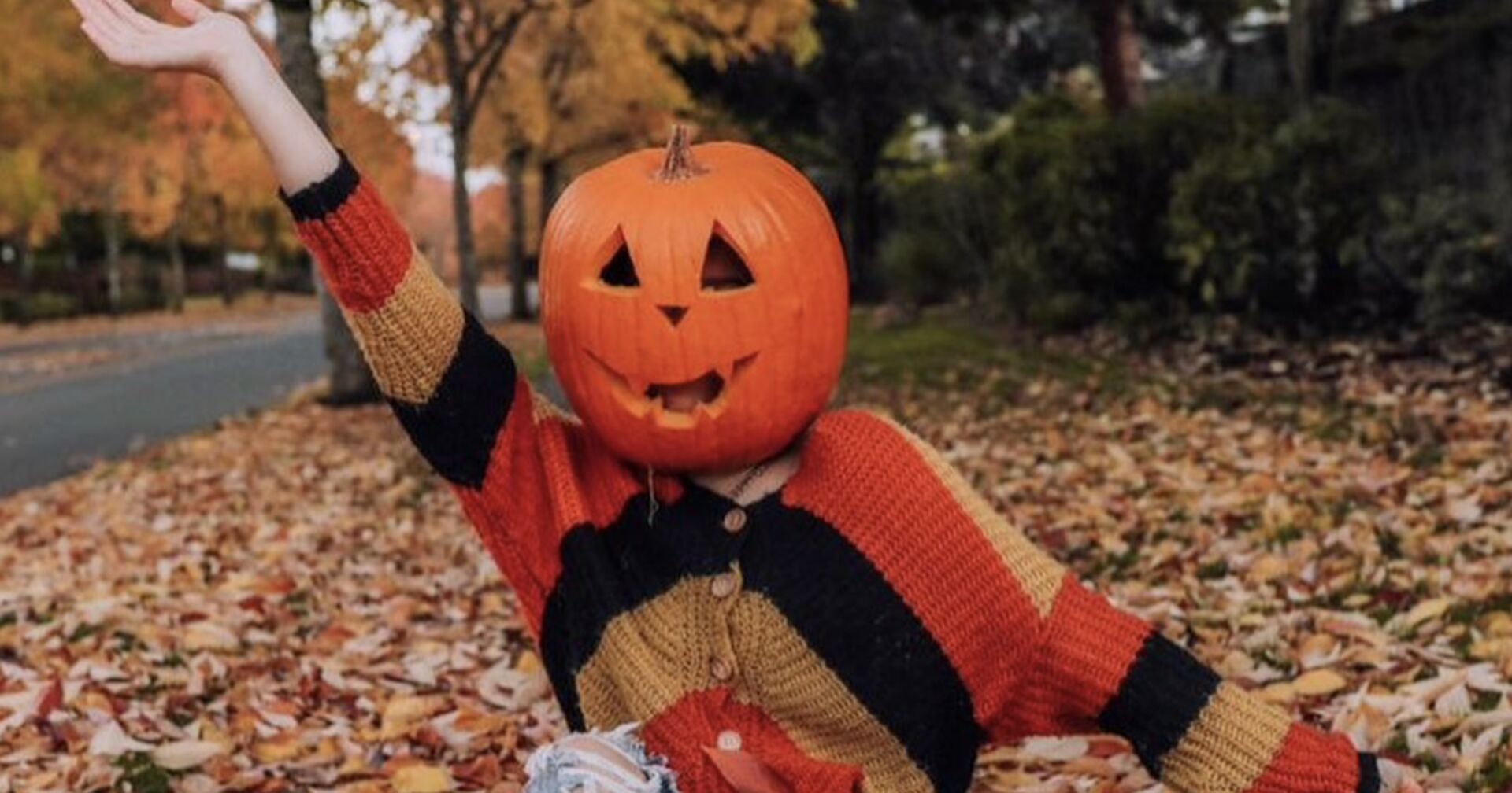 Frau mit Kürbis auf dem Kopf inmitten on Blättern
