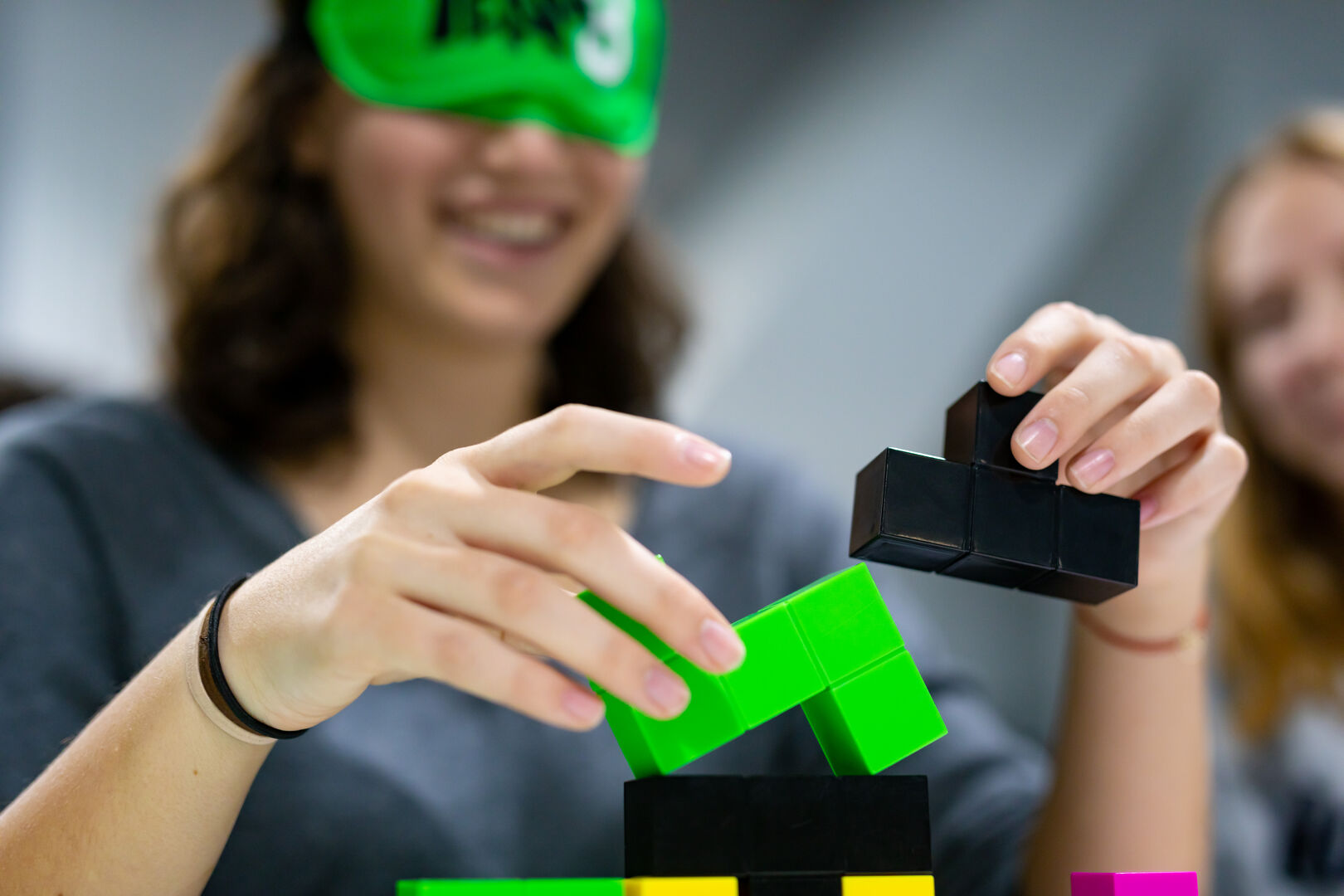 Mädchen mit verbundenen Augen probiert ein Tastspiel | acv.at/Ludwig Schedl