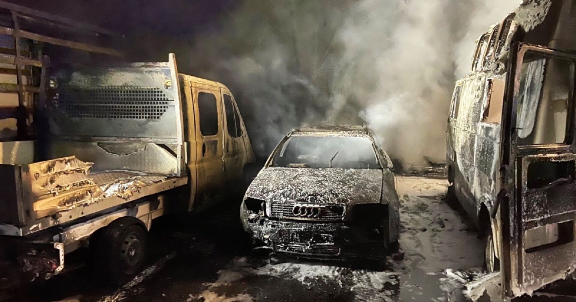 Ausgebrannte und aschbedeckte Fahrzeuge