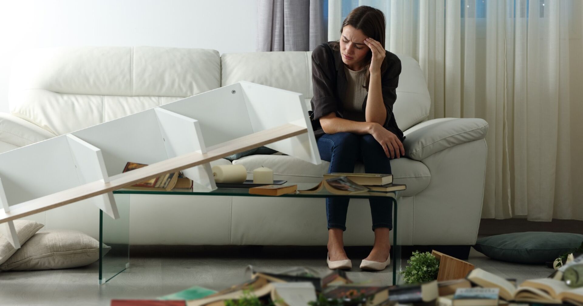 Frau sitzt traurig auf der Couch in der ausgeraubten Wohnung | Credit: iStock.com/AntonioGuillem
