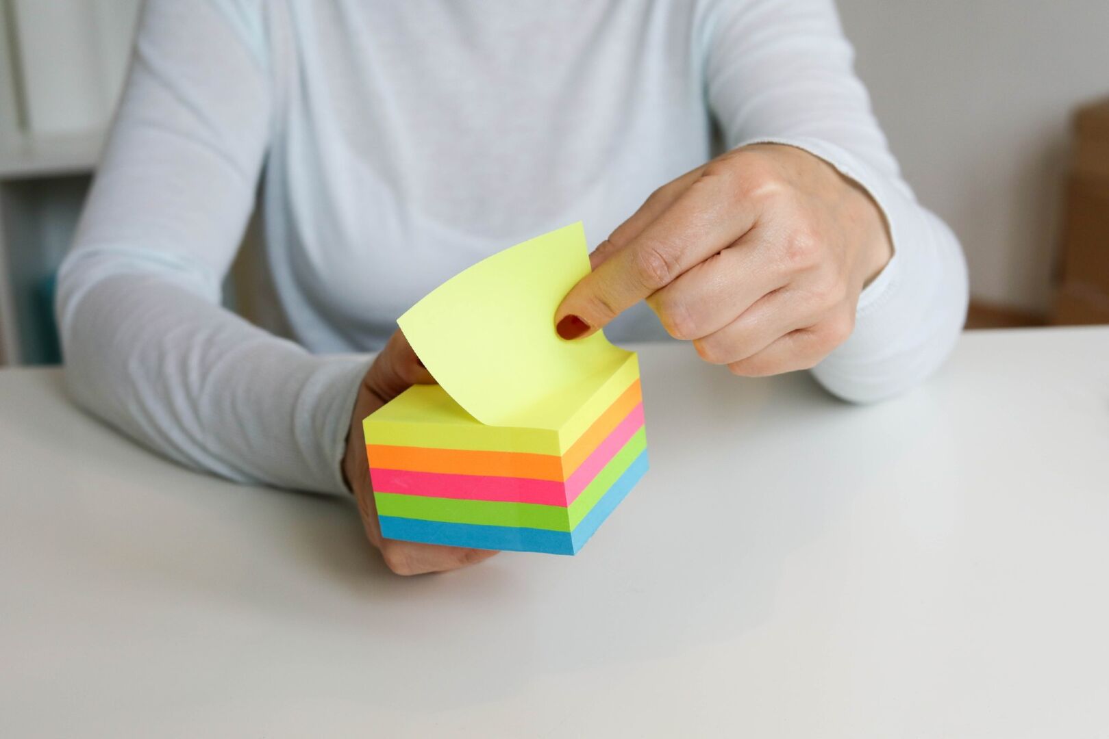 Frau hält einen Haftnotizen-Block in der Hand | Credit: iStock.com/Gabrijelagal