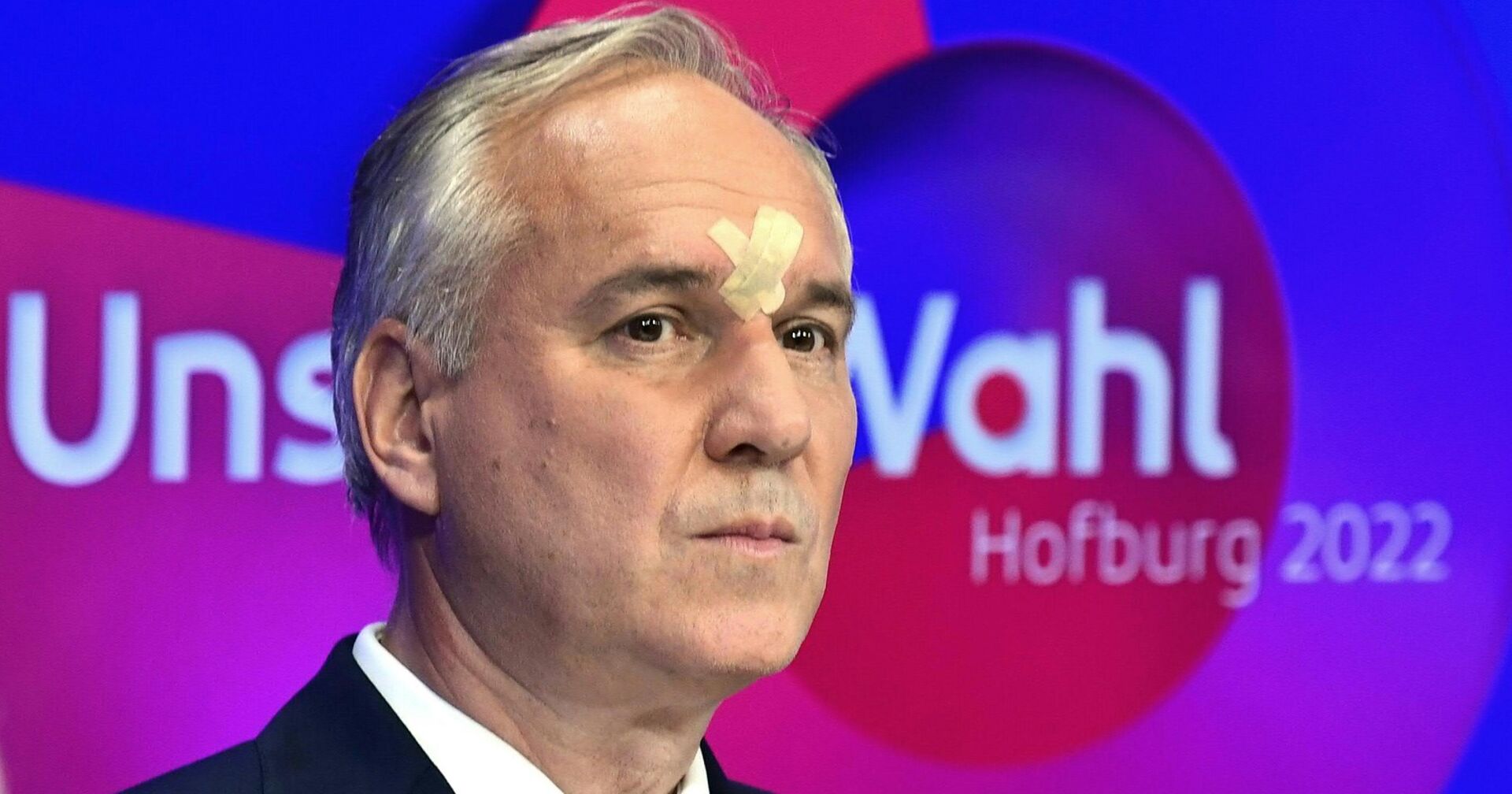 Walter Rosenkranz trägt zwei überkreuzte Pflaster auf der Stirn