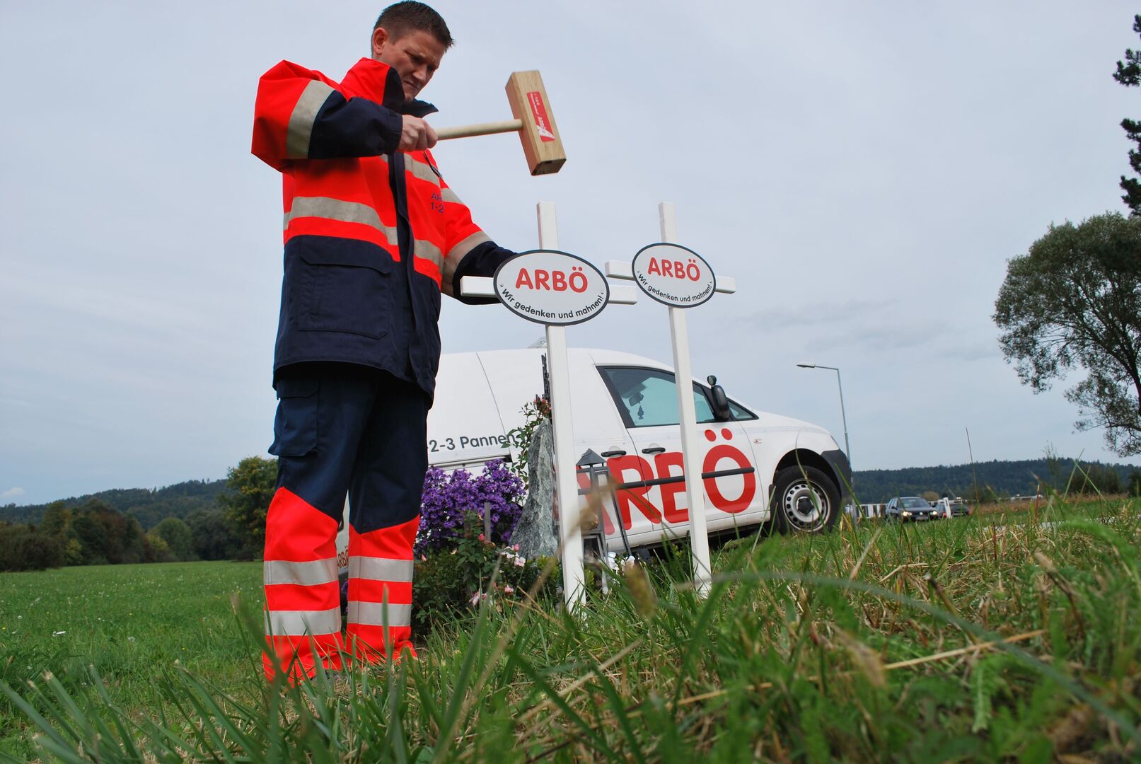 Mann bringt mit Hammer weiße Kreuze an Straßenrändern an