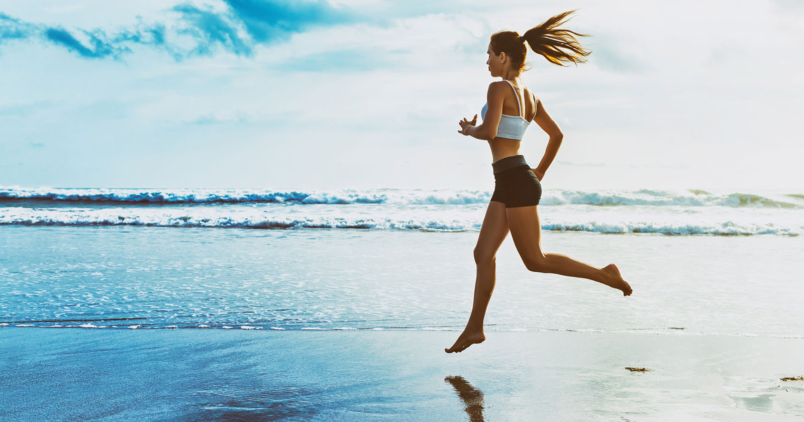 Junge Frau läuft den Strand entlang | Credit: iStock.com/Bicho_raro