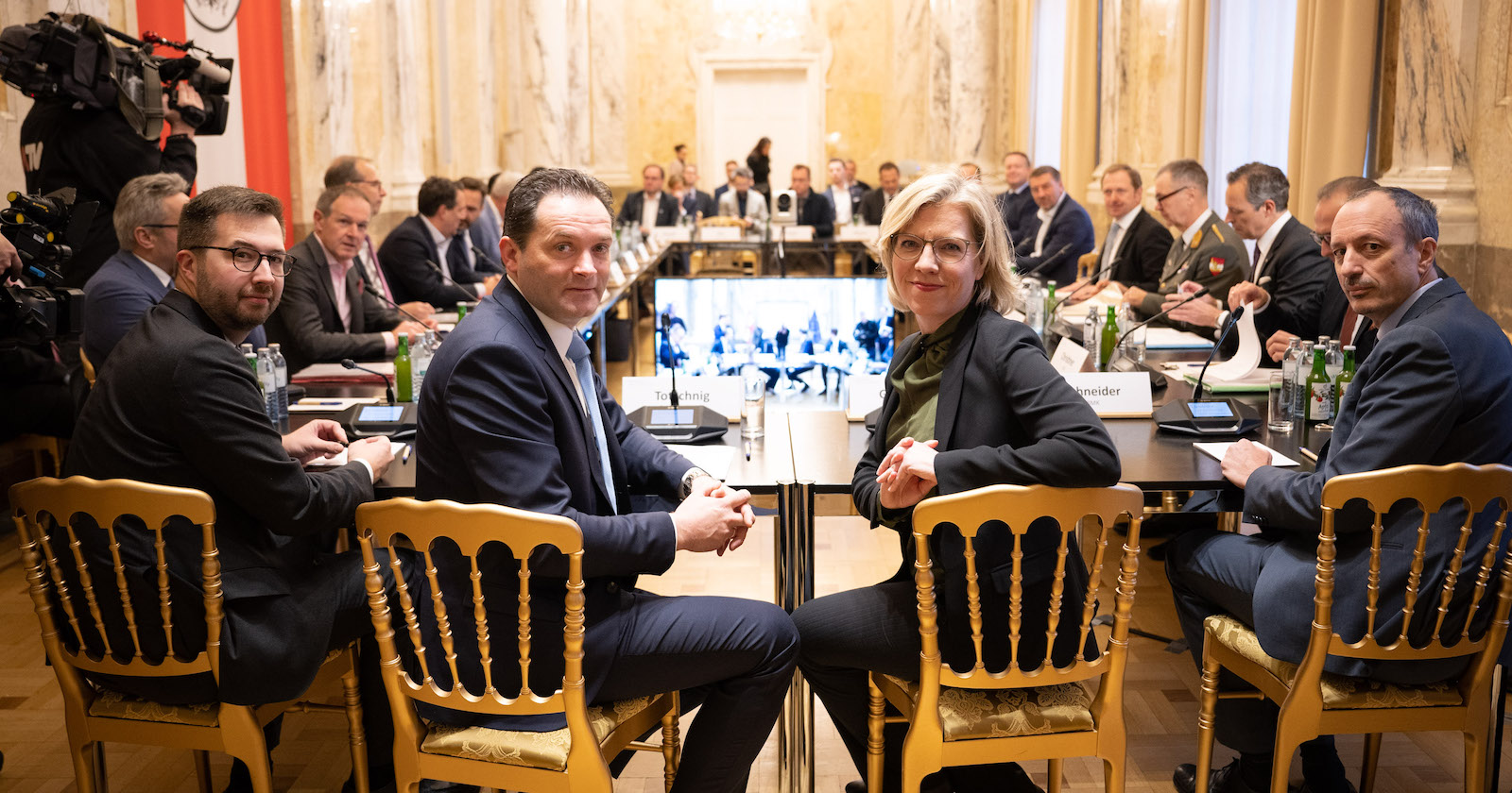 Menschen sitzen am Tisch, drehen sich Richtung Kamera um