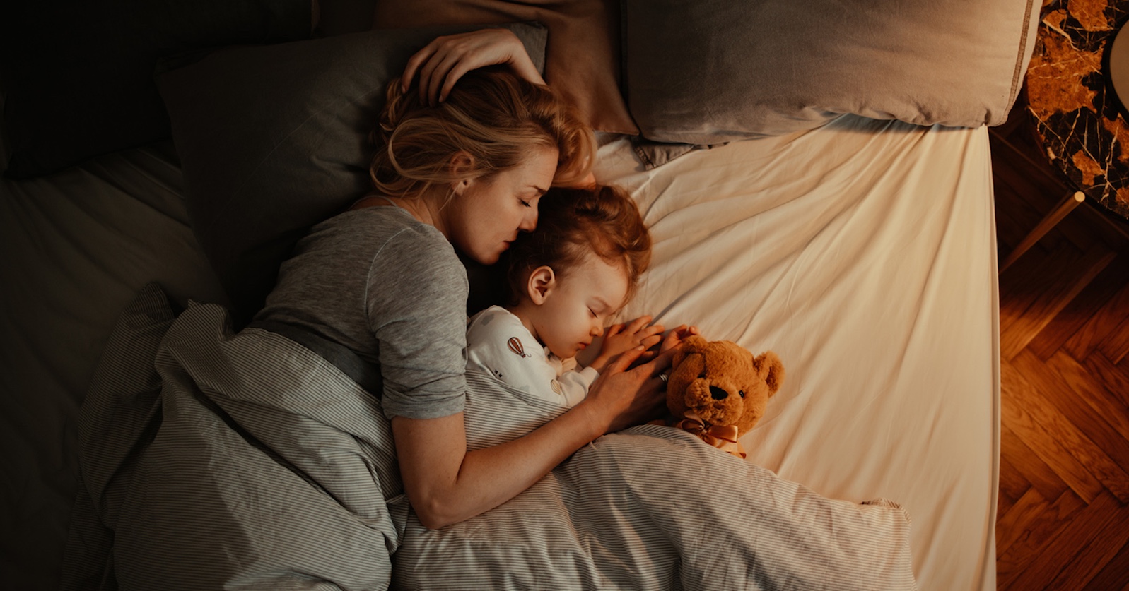 Frau schläft mit Kinder im Bett. | Credit: iStock.com/miniseries