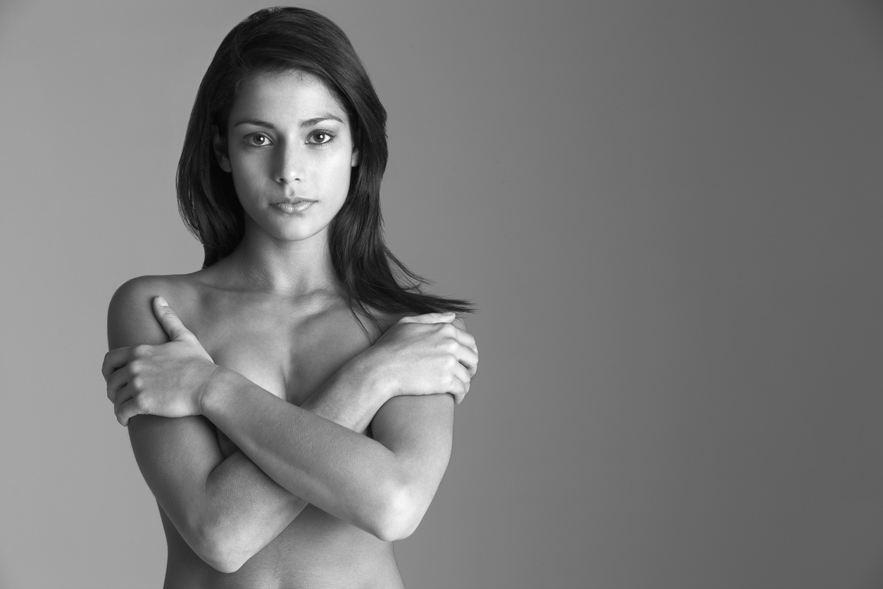 Nackte Frau in Schwarz-Weiß, die ihre Brüste bedeckt