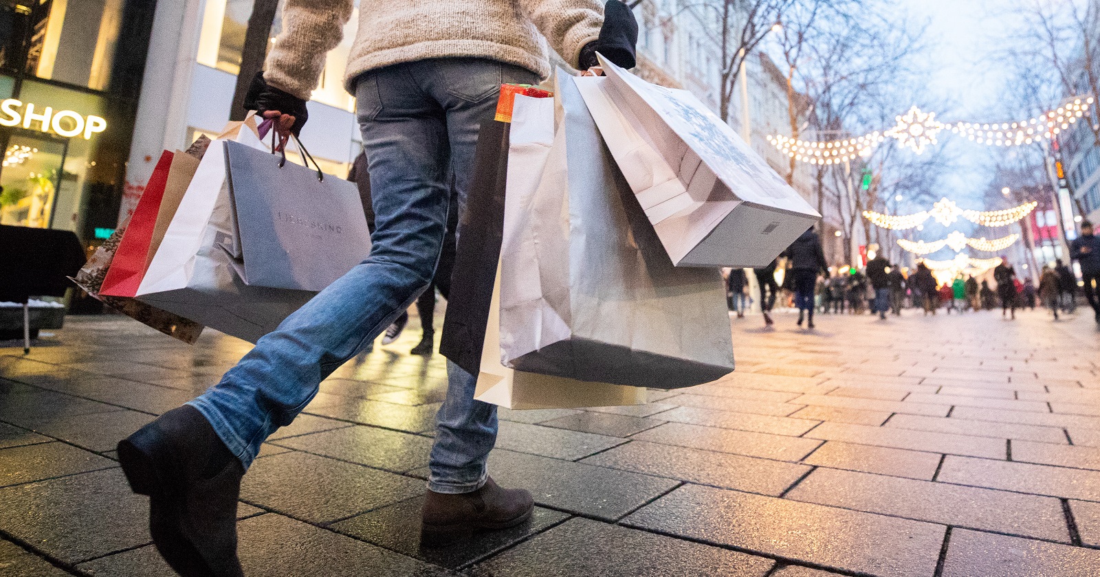 Eine Person mit mehreren Einkaufssackerln auf der weihnachtlich beleuchteten Mariahilferstraße